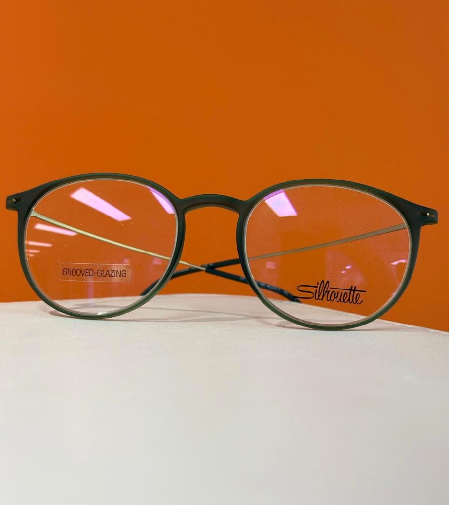 Silhouette Herbstneuheiten: nur bis 22. August in Oppenheim 5 Grüne runde Silhouette Brille vor orangefarbenem Hintergrund